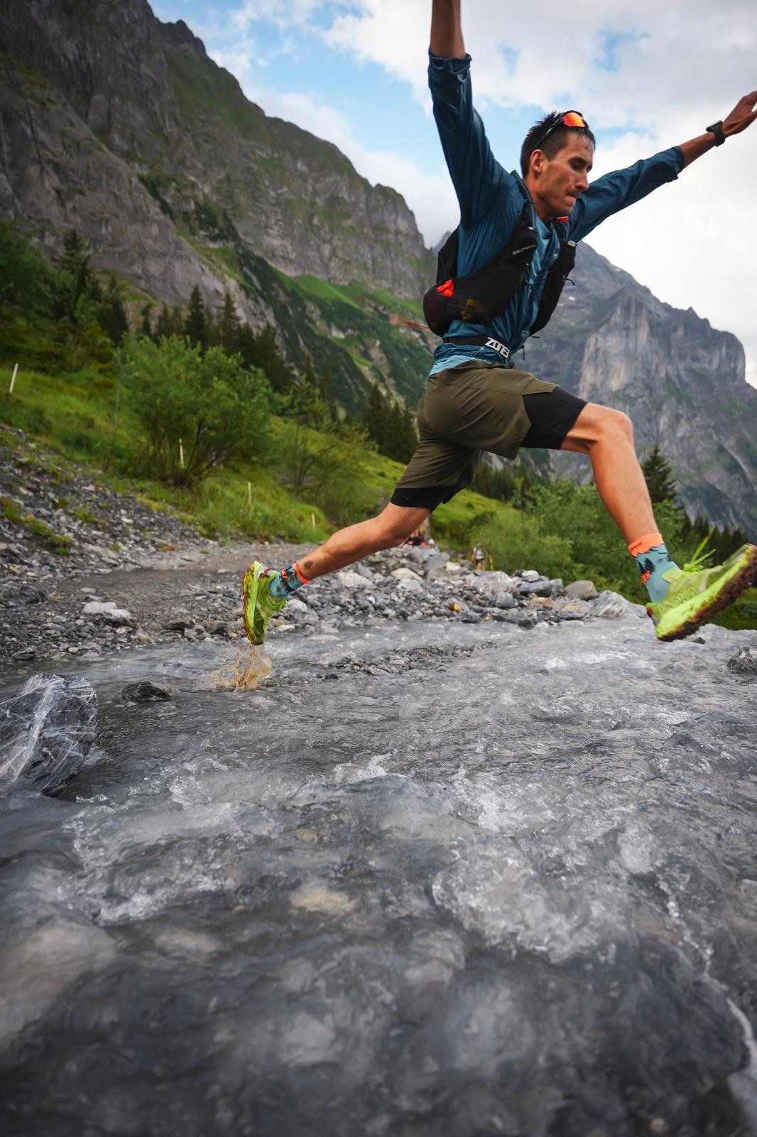 Tomasz Brachmański saltando un río de montaña durante una carrera de trail, parte de su preparación física